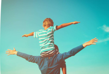 Father carrying son on shoulders - arms outstretched