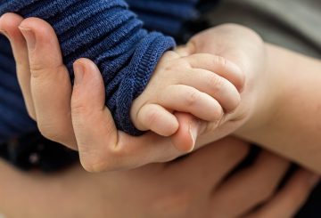 toddler's hand rests in adult's hand