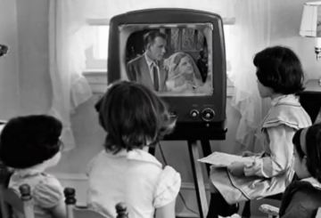 black and white photo of children watching an old TV screen showing a wedding