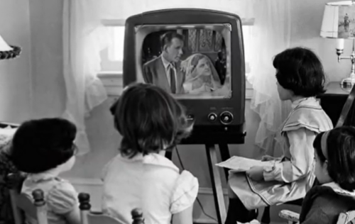 black and white photo of children watching an old TV screen showing a wedding