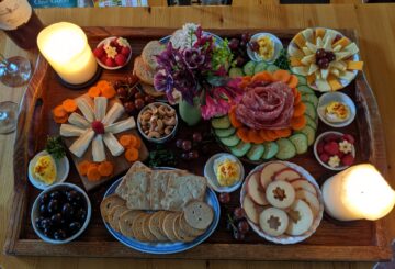 A board filled with meat, cheese and vegetables.