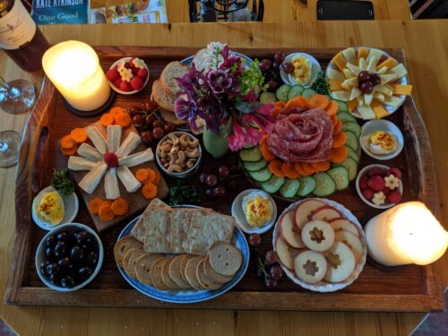 A board filled with meat, cheese and vegetables.